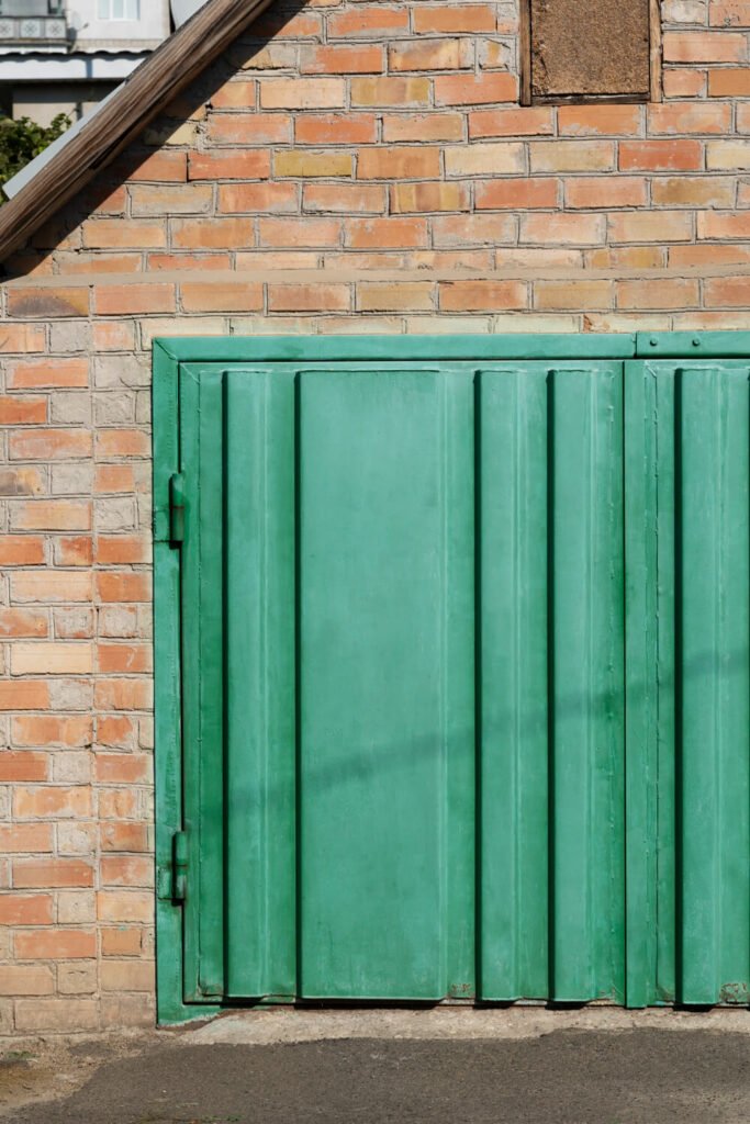 portón de hierro verde en pared de ladrillos